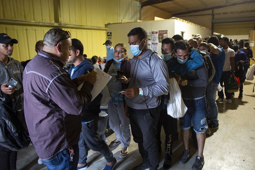 En esta imagen de archivo, un grupo de personas hace fila para subir a un autobús que los llevará al aeropuerto de San Antonio, en un almacén gestionado por la ONG Mission: Border Hope, de la Iglesia Metodista Unida, en Eagle Pass, Texas, el 23 de mayo de 2022.&nbsp;