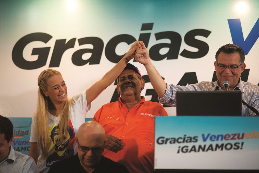 Lilian Tintori, esposa del líder opositor Leopoldo López, levanta lamano de Enrique Marquez, uno de los diputados electos en los recientes comicios (EFE)