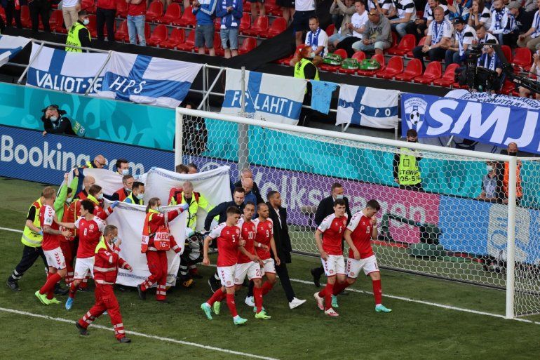 Los jugadores acompañan a los paramédicos mientras el mediocampista danés Christian Eriksen es evacuado del campo durante el partido de fútbol del Grupo B de la UEFA EURO 2020 entre Dinamarca y Finlandia