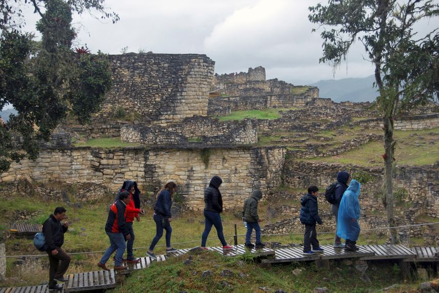 Una familia de turistas pasea en mitad de la lluvia frente al templo mayor de la ciudad fortificada de Kuélap, el mayor exponente arquitectónico de la civilización prehispánica Chachapoyas, en la región peruana de Amazonas.&nbsp;