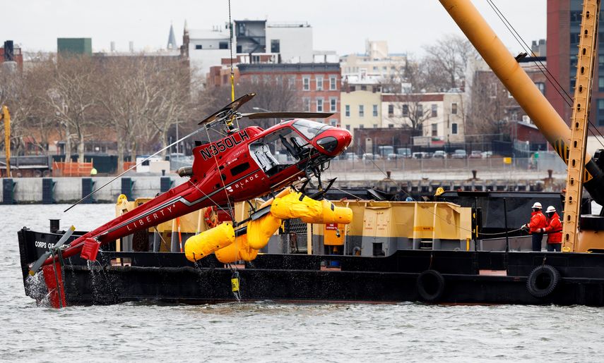 Una grúa saca al helicóptero del estrecho del East River de Nueva York.
