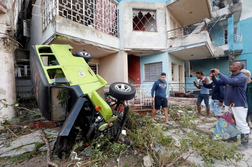 Vecinos de La Habana miran un auto lanzado contra una vivienda por el tornado que azotó la capital cubana en la madrugada del 28 de enero de 2019.