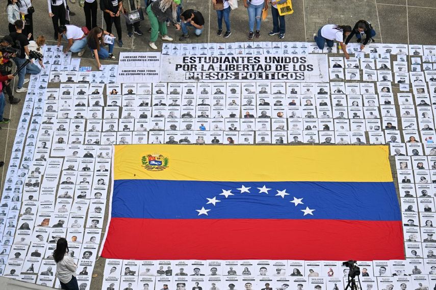 Personas muestran retratos de presos políticos durante una manifestación de familiares en la Universidad Central de Venezuela en Caracas el 13 de enero de 2026.