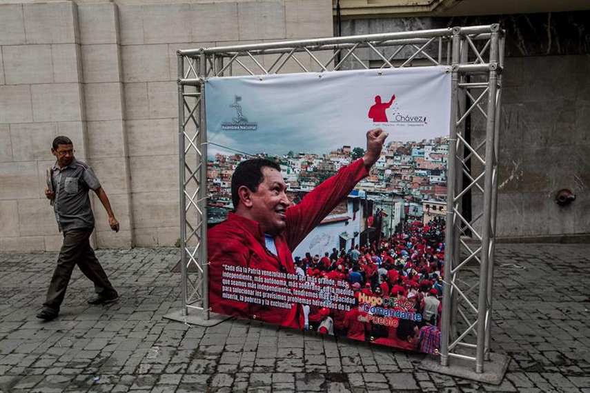Un hombre pasa cerca a una fotografía de una exposición callejera sobre el fallecido líder venezolano Hugo Chavez en los alrededores de la Asamblea Nacional en Caracas. (Foto: EFE)