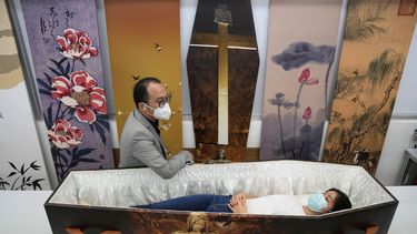 Wilson Tong, director general de LifeArt Asia, habla con una reportera que prueba un féretro de papel con temática católica en la fábrica de Tong, el viernes 18 de marzo de 2022, en Hong Kong.&nbsp;