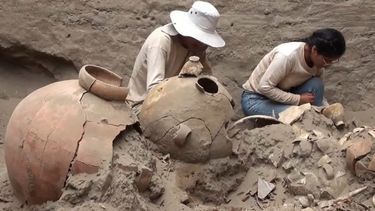 Esta imagen de folleto publicada por la Universidad Nacional Mayor de San Marcos y distribuida el 21 de mayo de 2023 muestra a los trabajadores descubriendo una tumba de 1.000 años de antigüedad de una figura de élite vinculada al mar de la cultura prehispánica Chancay en el sitio arqueológico funerario de Macaton en la costa de la provincia de Huaral, a unos 75 km al norte de Lima, Perú.