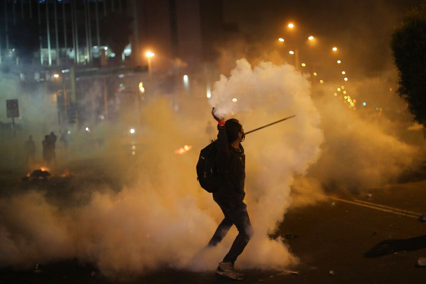 Un manifestante devuelve una lata de gas lacrimógeno lanzada por la policía para dispersar a inconformes el jueves 12 de noviembre de 2020, los cuales intentan aproximarse al Congreso en una protesta contra la remoción del presidente Martín Vizcarra, en Lima, Perú.