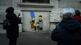 La gente toma fotos de un mural del artista callejero italiano AleXsandro Palombo titulado Pista 21 Los Simpson deportados a Auschwitz el 26 de enero de 2023 cerca de la estación central de trenes de Milán, con motivo del próximo Día Internacional del Recuerdo del Holocausto.