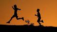 La silueta de dos niños se ve recortada contra el cielo al atardecer mientras corren por una colina en el Parque Papago, el 1 de abril de 2022 en Phoenix.&nbsp;