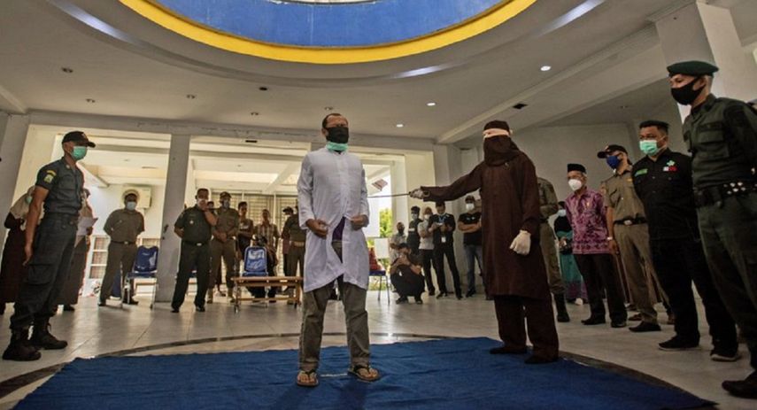 Un funcionario de Sharia emplea un bastón de caña para golpear a un hombre condenado por tener relaciones sexuales homosexuales en Banda Aceh, en la provincia de Aceh, Indonesia, el jueves 28 de enero de 2021