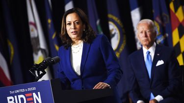 Kamala Harris habla a la audiencia, mientras Joe Biden observa atrás.