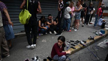 La gente carga sus teléfonos móviles desde un camión del municipio de Chacao durante un apagón en Caracas el 30 de agosto de 2024, que dejó a oscuras a Venezuela.