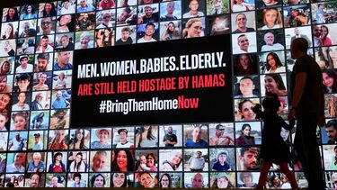 Un hombre y un niño pasan junto a un mural de fotos de rehenes israelíes secuestrados por terroristas de Hamás durante el letal ataque del 7 de octubre. Tel Aviv el 21 de noviembre de 2023.