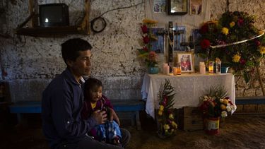 Ricardo García y su hija Ángela, sentados junto a un altar adornado con fotografías de su hija mayor, Santa García, en su casa en Comitancillo, Guatemala, el 27 de enero de 2021. García cree que el cuerpo de Santa es uno de los cadáveres calcinados hallados en un estado del norte de México.&nbsp;