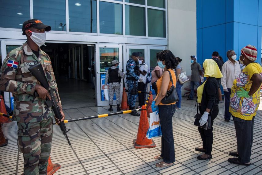 Las personas usan mascarillas pero no guardan la distancia social recomendada como medida preventiva contra la propagación del nuevo coronavirus, COVID-19. Los ciudadanos hacen cola en una calle de Santo Domingo, en República Dominicana, el 3 de abril de 2020.
