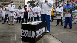 Trabajadores de la salud se paran alrededor de un ata&uacute;d simulado con la palabra corrupci&oacute;n y al nombre de la aseguradora nacional de salud de la entidad de seguridad social (ESSALUD) mientras protestan por la falta de equipo de protecci&oacute;n para el personal que atiende a pacientes con COVID-19, frente a un hospital p&uacute;blico en Lima, Per&uacute;, el martes 29 de septiembre de 2020.&nbsp;