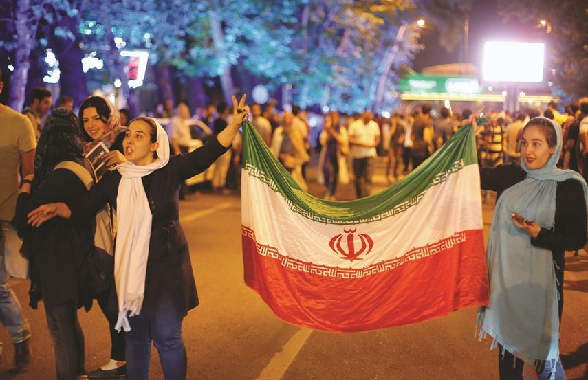 Iraníes sostienen banderas del país en una calle de Teherán, el martes 14 de julio. (EFE) 