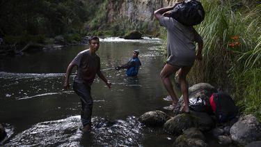 Leonel y Pedro ayudan a otro migrante venezolano en el río Guaitara a cruzar ilegalmente a Ecuador.