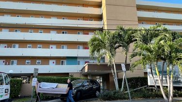 Dos personas sacan un mueble del edificio edificio Bayview 60 Homes, desalojado de manera urgente por las autoridades.&nbsp;