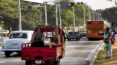 Varios veh&iacute;culos privados y estatales transitan por una calle de La Habana.