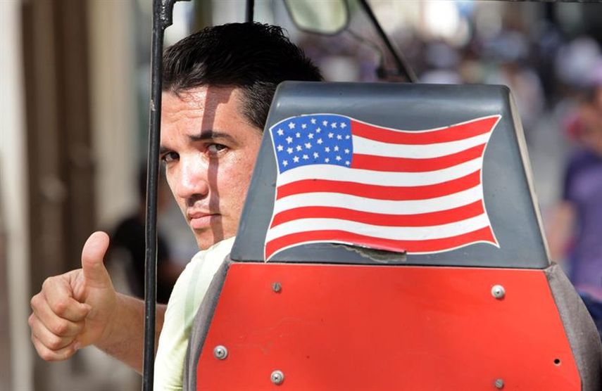 Un hombre saluda desde un bici-taxi, en La Habana, a pocas horas del reinicio oficial de las relaciones diplomáticas entre EEUU y Cuba. (EFE)