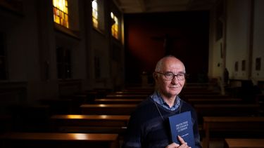 El diácono Jacques Beckand sostiene un libro utilizado durante las sesiones de exorcismo en el que se lee protección, liberación y curación mientras posa para una fotografía en una capilla del Hogar San José en Bruselas, el 11 de septiembre de 2024.&nbsp;