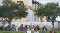 Estudiantes, maestros, familias de las víctimas y transeúntes observan, el viernes 14 de junio de 2024, cómo los equipos comienzan la demolición del edificio de la escuela secundaria Marjory Stoneman Douglas, donde 17 personas murieron en el tiroteo masivo de 2018 en Parkland, Florida.&nbsp;