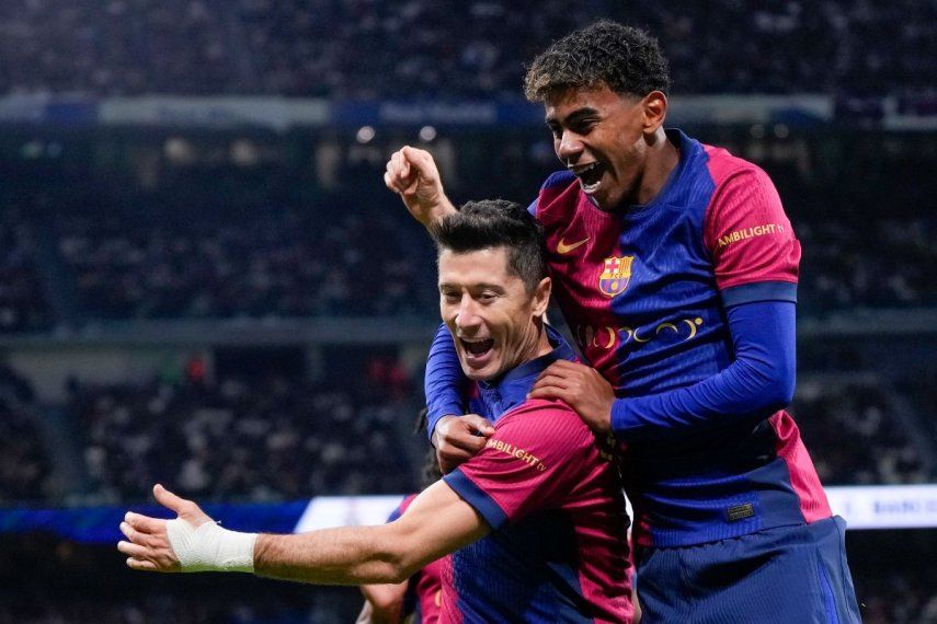 Robert Lewandowski, del Barcelona, celebra con Lamine Yamal después de anotar el segundo gol de su equipo durante un partido de fútbol de La Liga española entre el Real Madrid y el Barcelona en el estadio Santiago Bernabéu en Madrid, España, el sábado 26 de octubre de 2024.