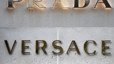 Esta combinación de imágenes, creada el 10 de abril de 2025, muestra una imagen de archivo del logotipo de la tienda de Versace, y del logotipo en el exterior de la tienda de la casa de moda y artículos de lujo Prada en París. &nbsp;