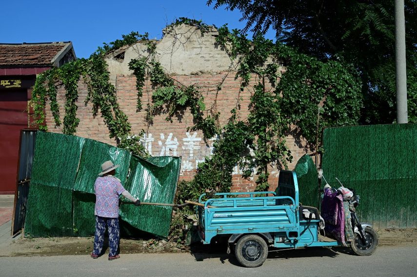 Mujeres recogen parte de un mural en el suelo cerca del epicentro del terremoto en el condado rural de Pingyuan de Shandong el 6 de agosto de 2023.