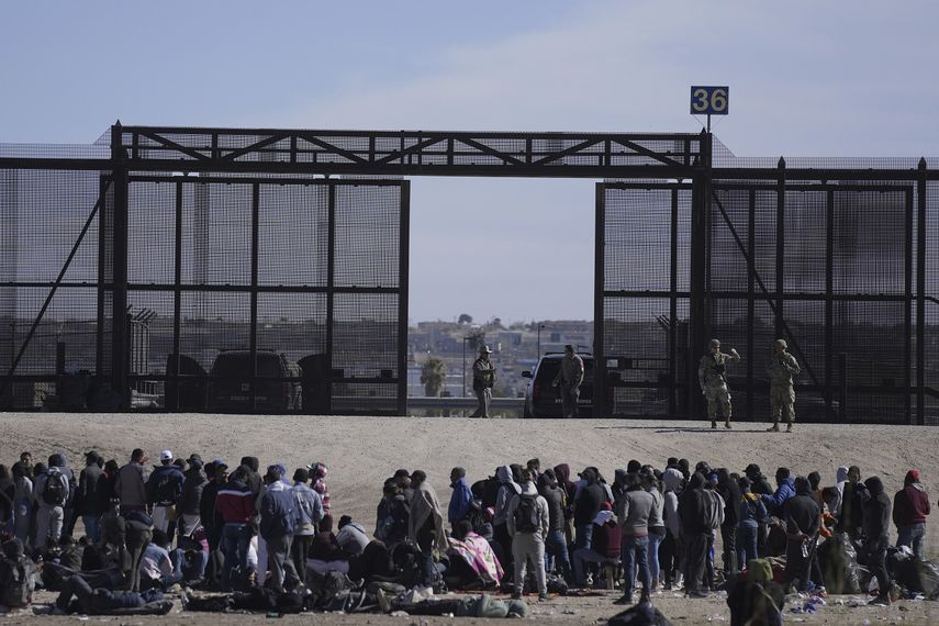 Migrantes que cruzaron la frontera desde México hacia Estados Unidos esperan a un costado del muro fronterizo en donde agentes de la Patrulla Fronteriza de Estados Unidos montan guardia, el 30 de marzo de 2023, en una imagen tomada desde Cuidad Juárez, México.&nbsp;
