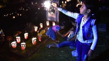 Una niña juega con una velita de pólvora junto a una tumba en un cementerio de Cali.&nbsp;