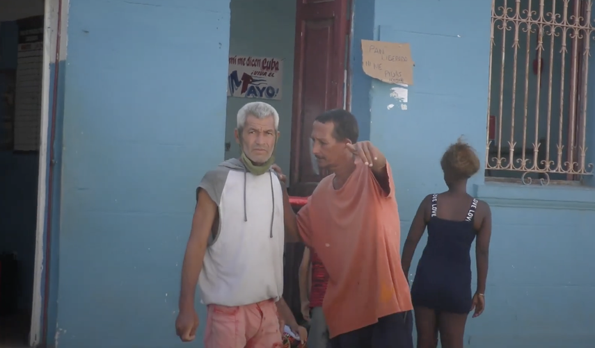 Cubanos frente a un cartel de venta de pan.&nbsp;