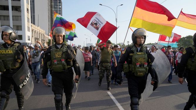 Policía antimotines camina delante de manifestantes de oposición al gobierno que marchan contra la presidenta Dina Boluarte en Lima, Perú, el lunes 23 de enero de 2023.