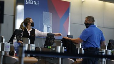 Empleada de Delta Air Lines le entrega un boleto a un pasajero.