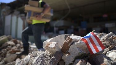 Una bandera de Puerto Rico se ve colocada entre los escombros, mientras los propietarios y familiares retiran suministros de la ferretería Ely Mer Mar, parcialmente derruida tras un terremoto en Guanica, Puerto Rico, el martes 7 de enero de 2020.