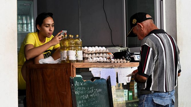 Comprar comida básica es un lujo en la isla. Hombre busca el dinero frente a una tienda de alimentos.