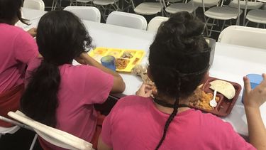 Niños inmigrantes toman alimentos en un refugio para menores no acompañados.