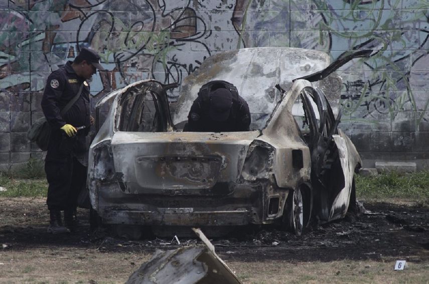 Policías revisan los restos de un cocho bomba que explotó mientras las autoridades respondían a reportes de un vehículo con un cuerpo dentro en el barrio de San Bartolo, Soyapando, El Salvador, el lunes 29 de abril de 2019