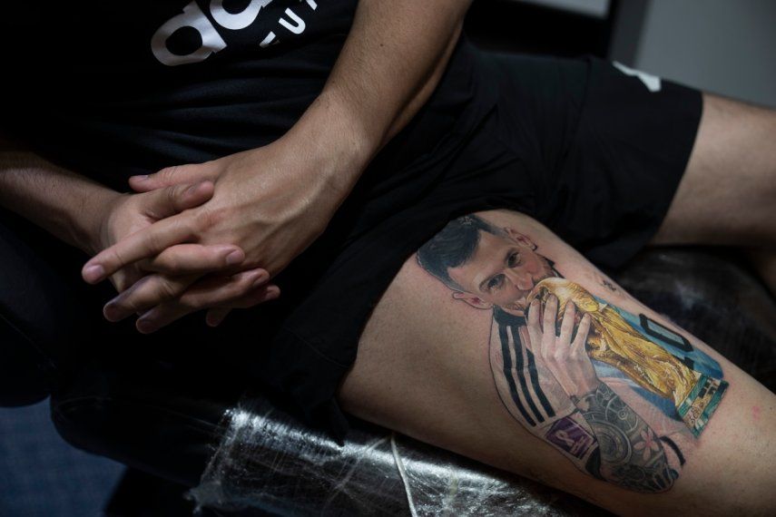 Sebastián Fernández descansa mientras el artista César Yeyo Molina le tatúa en la pierna una imagen del futbolista Lionel Messi besando la Copa del Mundo en Buenos Aires, Argentina, el jueves 29 de diciembre de 2022.&nbsp;