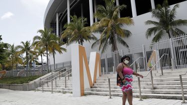 Una mujer con una mascarilla camina frente al estadio Marlins Park de Miami, el lunes 27 de julio de 2020.&nbsp;
