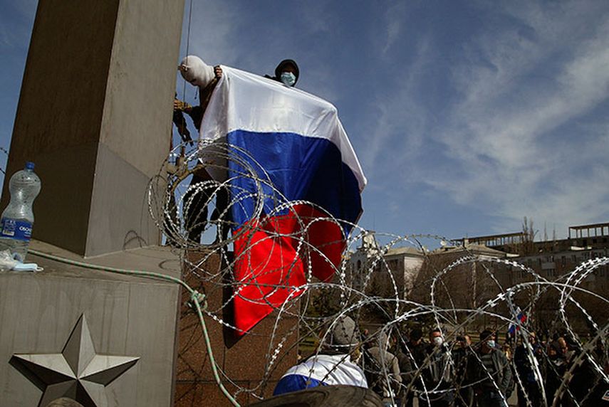 Un hombre sostiene una bandera de Rusia mientras está de pie sobre una barricada colocada en un edificio del gobierno en Donetsk, este de Ucrania. Separatistas prorrusos proclamaron el lunes independiente la región de Donetsk en un suceso que hace eco