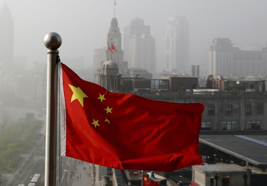 Foto tomada el 14 de abril del 2016 de una bandera china junto a varios edificios en Shanghái. Una serie transmitida por el canal estatal CCTV muestra la corrupción en el gigante asiático.
