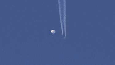 En esta foto proporcionada por Brian Branch, un gran globo se desplaza por encima de la zona de Kingstown, Carolina del Norte, mientras por debajo se observa un avión y la estela que deja a su paso. 