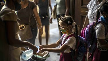 Con una máscara como medida de precaución en medio de la propagación del nuevo coronavirus, una estudiante se lava las manos al llegar a la escuela en La Habana, Cuba, el lunes 2 de noviembre de 2020. Decenas de miles de niños regresaron a clases el lunes en La Habana para el primera vez desde que la pandemia de coronavirus llevó a las autoridades a cerrar la isla en abril.