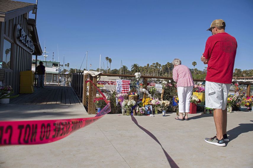 Dos personas observan un monumento conmemorativo improvisado colocado en honor de las víctimas de un incendio en un bote de buceo mientras las autoridades allanaban las oficinas de Truth Aquatics, la compañía propietaria de la embarcación, en Santa Barbara, California, el domingo 8 de septiembre de 2019.&nbsp;