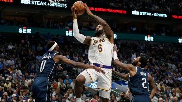 El alero de los Lakers de Los Ángeles, LeBron James, lanza el balón frente a Justin Holiday y Kyrie Irving de los Mavericks de Dallas en el encuentro del domingo 26 de febrero del 2023.