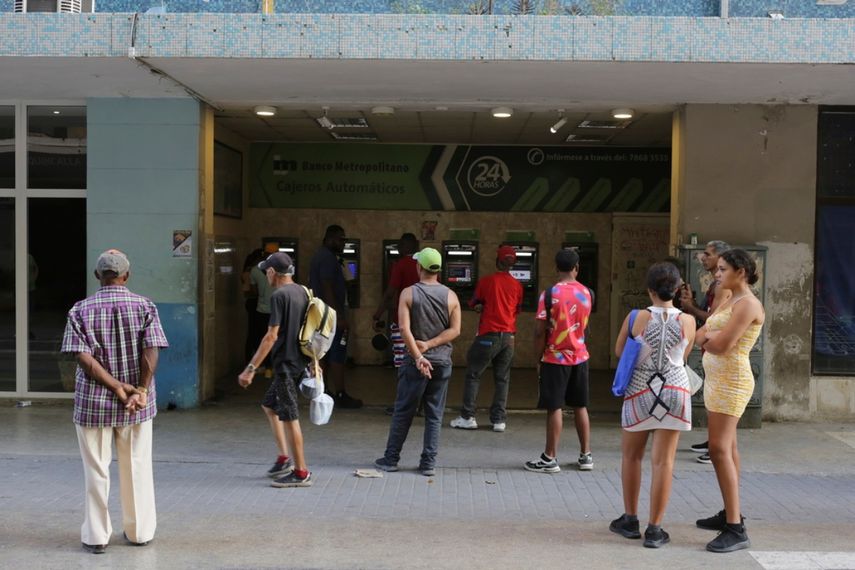 Varias personas esperan en el exterior de un banco para poder retirar pesos cubanos de un cajero automático, en La Habana.