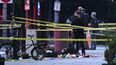 Un investigador forense toma fotos detrás de una cinta policial que protege la escena del crimen, con marcadores de evidencia visibles en una acera en la 17ª y la avenida Pennsylvania cerca de la Casa Blanca en Washington, DC, el 23 de mayo de 2026.