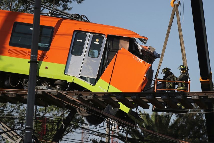 Bomberos trabajando para descolgar hasta el suelo un vagón de metro que quedó suspendido en un tramo elevado del metro, en Ciudad de México, el martes 4 de mayo de 2021. Al menos 24 personas murieron y más de 70 resultaron heridas tras el desplome de un paso elevado del metro.